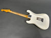 Vintage white electric guitar body with visible wear and aging, maple neck with skunk stripe, and chrome neck plate, back view on gray background