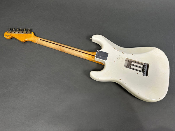 Vintage white electric guitar body with visible wear and aging, maple neck with skunk stripe, and chrome neck plate, back view on gray background