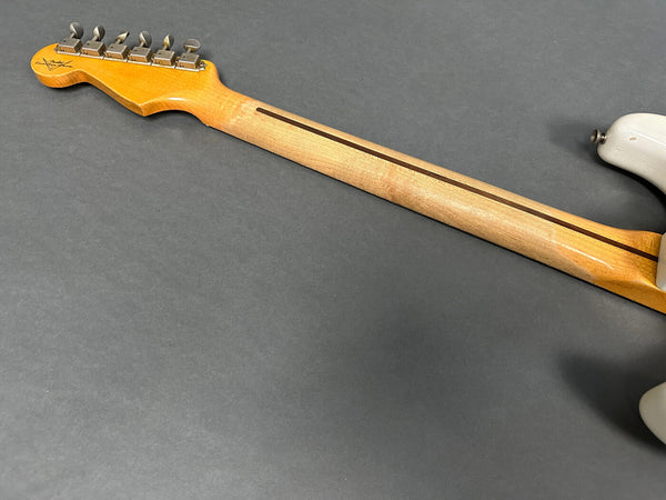 Back view of natural maple neck and vintage tuners on electric guitar with signed headstock and off-white body on gray background