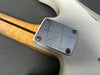 Vintage Fender electric guitar neck plate with serial number GZ528637 on a worn white guitar body with a maple neck and skunk stripe on a gray background