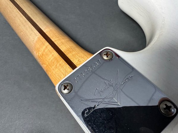 Close-up of Fender guitar neck plate with serial number CZ526637 and maple neck on gray background