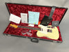 Fender electric guitar in vintage white finish inside open black hard case with red plush interior, including Fender certificate of authenticity, paperwork, and accessories.