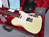 Vintage white Fender Telecaster electric guitar in open black hard case with red plush interior, showing Fender Custom Shop paperwork and accessories.
