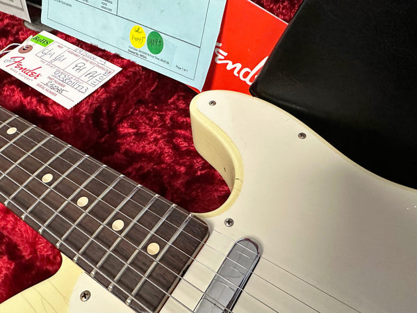 Close-up of vintage Fender Telecaster electric guitar body and fretboard inside red plush-lined hard case with Fender tag and documentation