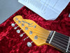 Close-up of Fender Telecaster guitar headstock on red plush case lining with maintenance checklist paper