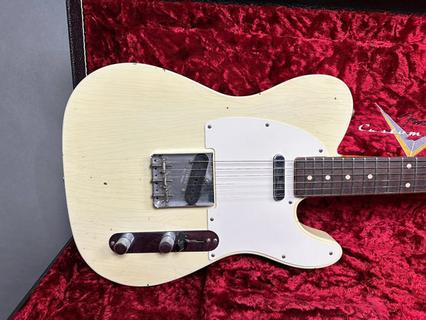Vintage cream electric guitar body with white pickguard and metal bridge, resting on red plush interior of custom guitar case
