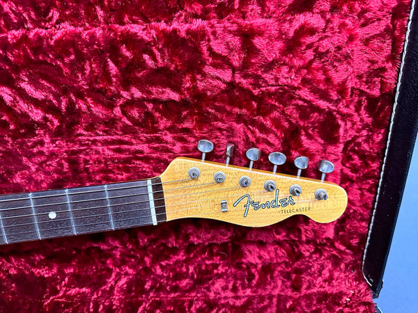 Fender Telecaster electric guitar headstock with six tuning pegs on red plush guitar case lining