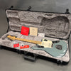 Fender electric guitar in seafoam green finish with maple neck, displayed in an open hard guitar case with plush gray interior, accompanied by Fender authenticity certificate, tags, and accessories.
