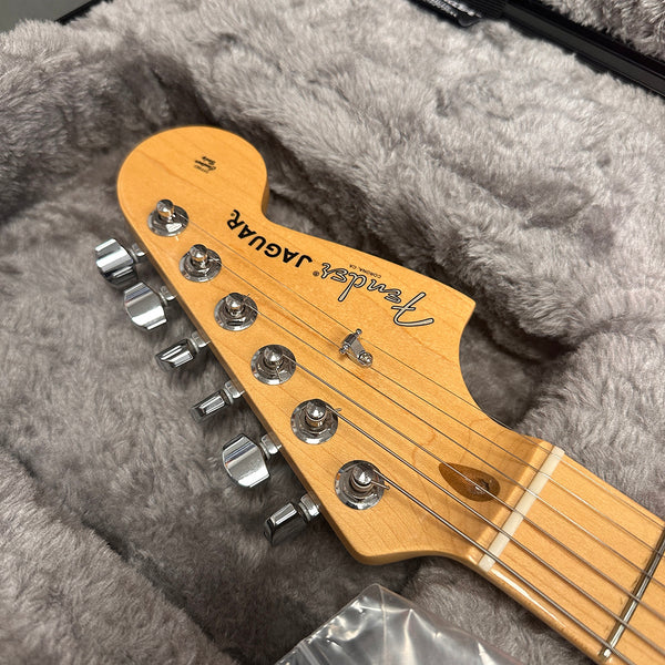 Close-up of Fender Jaguar maple guitar headstock with chrome tuning pegs inside a gray plush guitar case