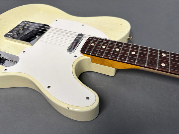 Close-up of vintage cream-colored electric guitar body and rosewood fretboard on gray background