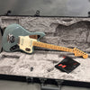 Fender Jaguar electric guitar in grey finish with maple neck and white pickguard resting inside a plush grey hard case with Fender accessory pouch.