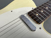 Close-up of vintage cream electric guitar body showing metal single-coil pickup and rosewood fretboard with dot inlays and metal frets