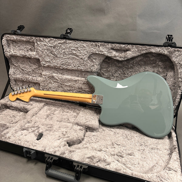 Back of seafoam green electric guitar with maple neck in gray plush-lined hard case with black exterior and handle