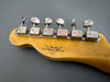 Close-up of Fender Custom Shop vintage guitar tuning pegs on natural maple headstock with logo on gray background