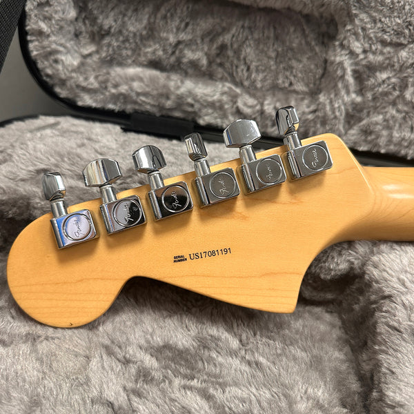 Close-up of Fender guitar maple neck headstock with six chrome tuning pegs and serial number US17081191 on gray plush guitar case lining
