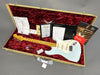 Fender Custom Shop electric guitar in light blue with maple neck and vintage tuning pegs, displayed inside a tweed hardshell case with red plush interior, including certificate of authenticity, owner's manual, and additional documents.