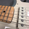 Close-up view of electric guitar strings, white single-coil pickup, and maple fretboard with dot inlay on light-colored guitar body