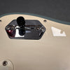 Close-up of a white electric guitar body showing a chrome pickup selector switch plate and black toggle switch knob with screws and light reflections.