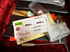 Fender guitar inspection tag and paperwork with tremolo arm and bubble wrap on red velvet background