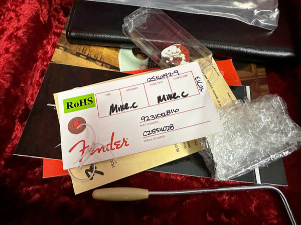 Fender guitar inspection tag and paperwork with tremolo arm and bubble wrap on red velvet background