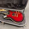 Electric guitar with sunburst finish, gold hardware, and humbucker pickups in a gray plush-lined hard case