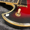 Close-up of electric guitar toggle switch with cream-colored tip on red and black sunburst body featuring mother of pearl and cream binding detail