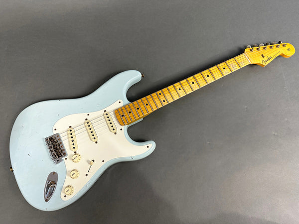 Light blue Fender Stratocaster electric guitar with maple neck and vintage white pickguard on gray background