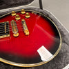 Close-up of red sunburst electric guitar body with gold hardware and bridge inside a padded guitar case