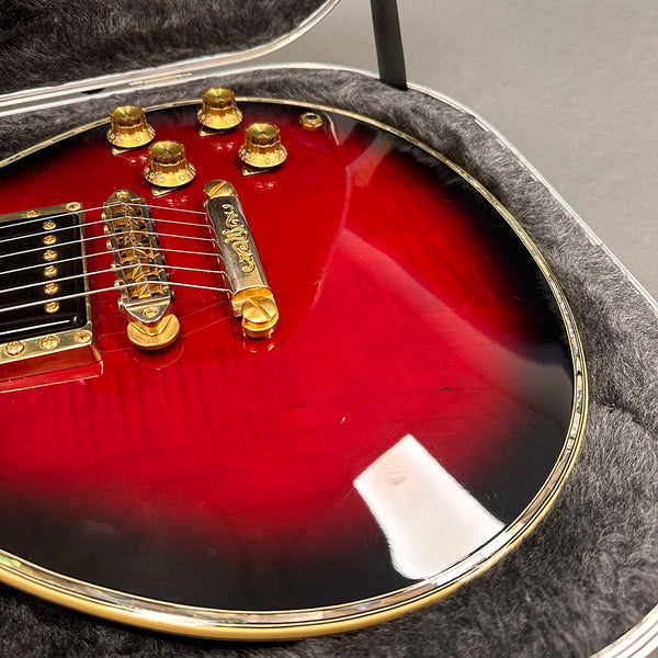 Close-up of red sunburst electric guitar body with gold hardware and bridge inside a padded guitar case