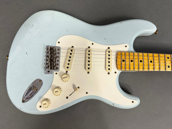 Vintage light blue electric guitar with three single-coil pickups, maple fretboard, and white pickguard on gray background