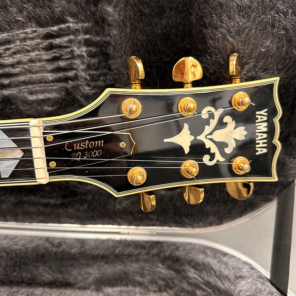 Yamaha Custom SG 3000 electric guitar headstock with gold tuning pegs and decorative inlay on black background