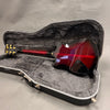 Electric guitar with red sunburst finish and gold tuning pegs displayed inside gray plush-lined black hard case