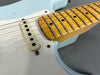 Close-up detail of light blue electric guitar body with white single-coil pickup and maple neck fretboard featuring dot inlays and steel frets