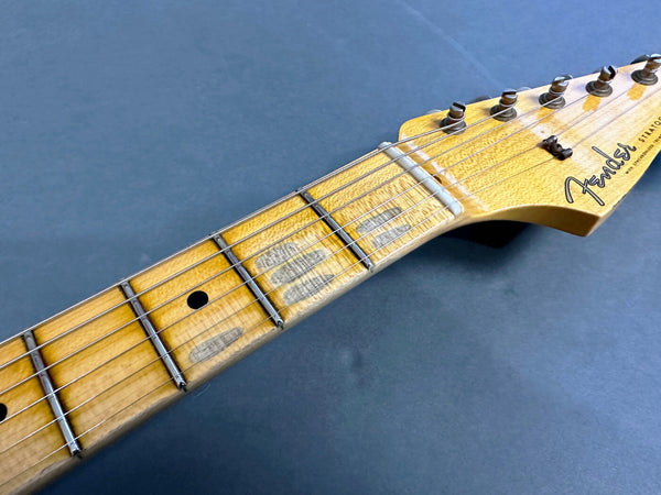 Close-up of Fender Stratocaster maple neck and headstock showing tuning pegs and fretboard on dark background
