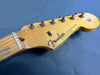 Close-up of Fender Stratocaster guitar headstock with six tuning pegs on blue background