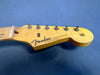 Close-up of vintage Fender Stratocaster guitar headstock with original contour body decal on blue background