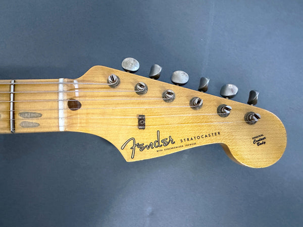 Close-up of vintage Fender Stratocaster guitar headstock with original contour body and six tuning pegs on gray background