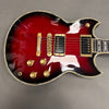 Electric guitar with red sunburst finish, gold hardware, and black humbucker pickups on a gray surface
