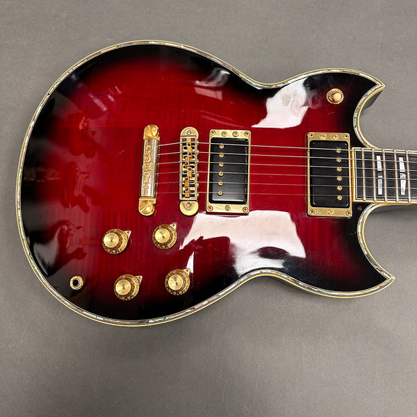 Electric guitar with red sunburst finish, gold hardware, and black humbucker pickups on a gray surface