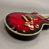 Close-up of red sunburst electric guitar body with gold hardware and control knobs on gray background