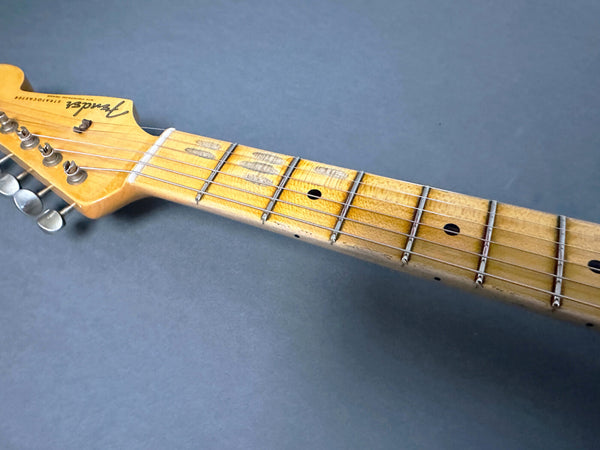 Close-up of vintage Fender Stratocaster guitar headstock and worn maple neck with tuning pegs on grey background