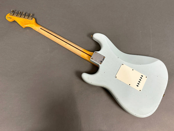 Vintage-style electric guitar with light blue body and maple neck showing back view and metal neck plate on gray background