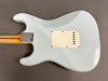 Back of vintage white Fender Stratocaster electric guitar showing neck plate and tremolo cavity cover with wear and checking on finish