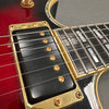 Close-up of electric guitar gold pickup and red sunburst body with pearl inlays on rosewood fretboard at Coffee House Guitars