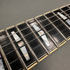 Close-up of guitar fretboard showing mother of pearl block inlays and metal frets on dark wood fingerboard