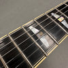 Close-up of electric guitar fretboard with mother-of-pearl inlays and metal frets on dark wood fingerboard