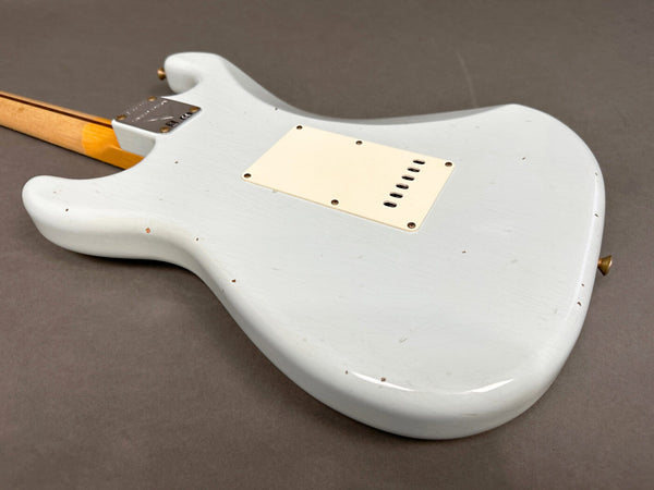 Close-up of the back body of a vintage white electric guitar with a cream-colored backplate and visible wear and aging marks, on a gray background.