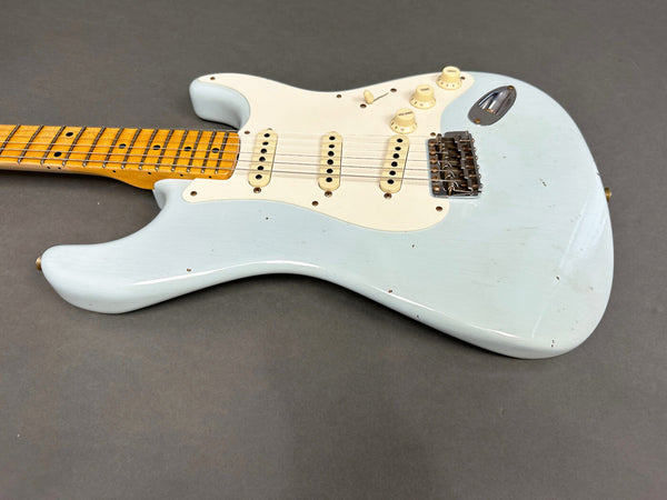 Vintage light blue electric guitar with maple neck and three single-coil pickups on gray background
