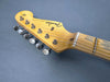 Close-up of vintage Fender Stratocaster electric guitar maple neck and headstock with tuning pegs and strings on gray background