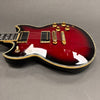 Close-up of red and black electric guitar body with gold hardware and control knobs on gray background